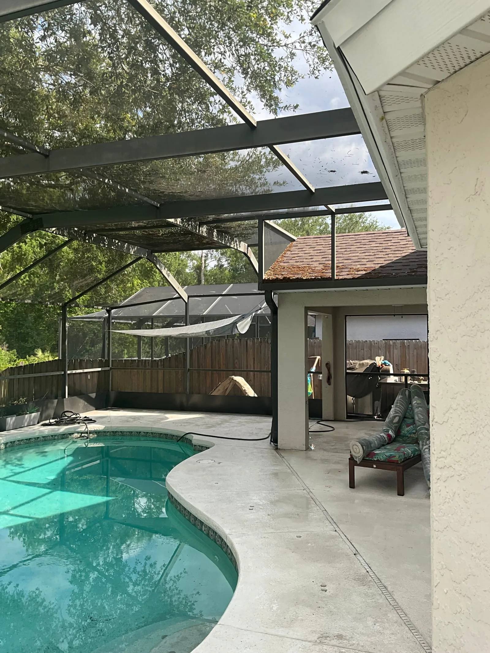 Pool deck cleaning in Tampa around a residential pool with a wider backyard deck view