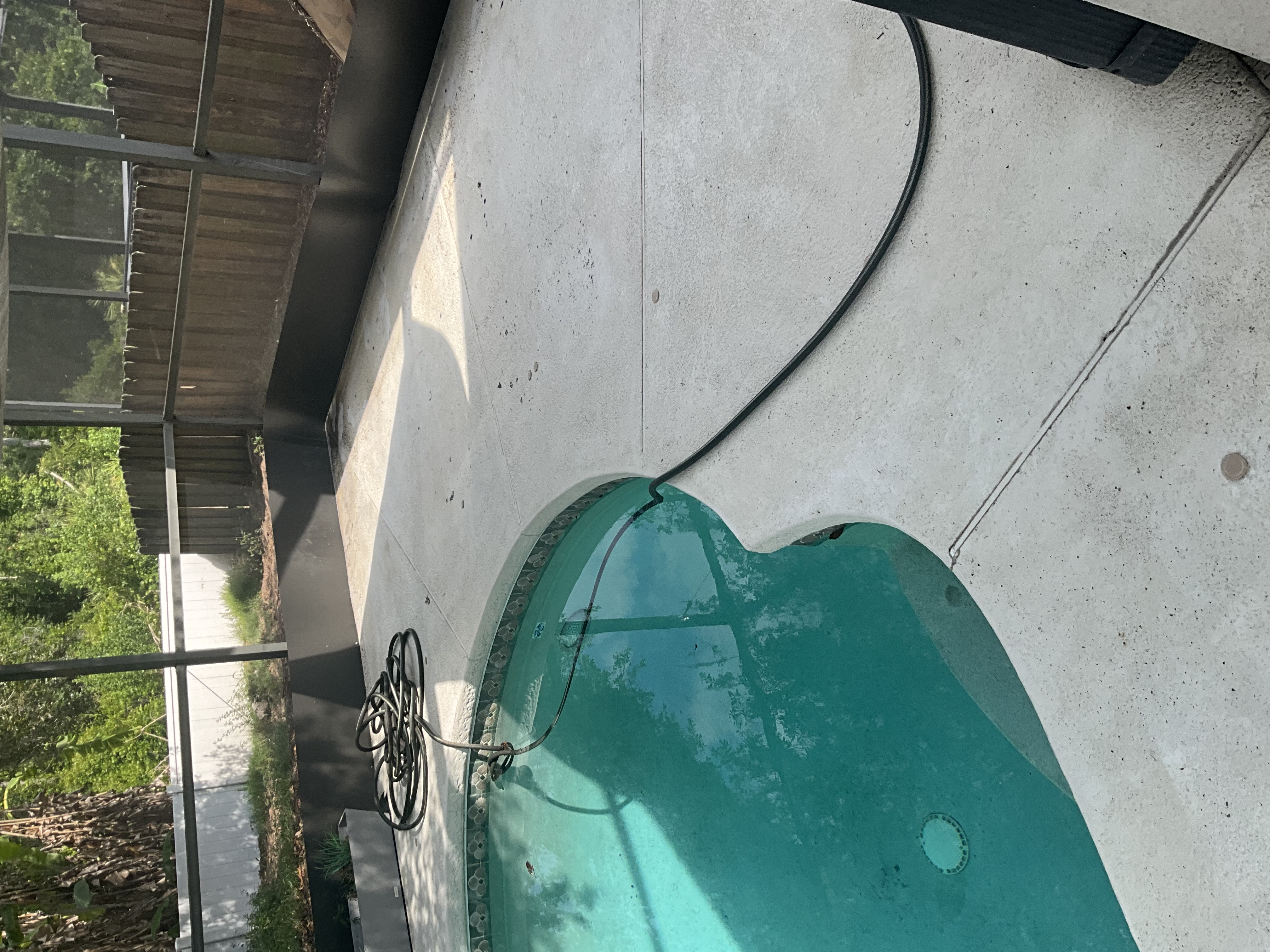 Pool deck surface in Tampa showing buildup along the deck edge near the water